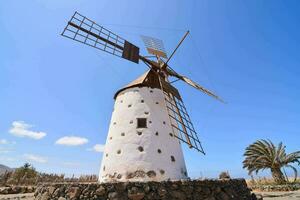 een windmolen in de midden- van een woestijn met palm bomen foto