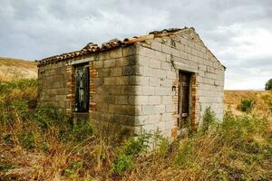 een oud steen gebouw in de midden- van een veld- foto