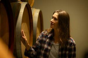 portret van een jong vrouw omringd door wijn vaten in haar wijnmakerij foto
