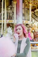 roze haar- meisje kort kapsel poseren in amusement park Aan carrousel achtergrond. foto