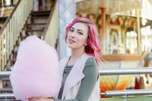 roze haar- meisje kort kapsel poseren in amusement park Aan carrousel achtergrond. foto