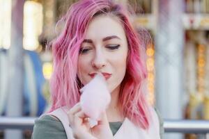 roze haar- meisje kort kapsel poseren in amusement park Aan carrousel achtergrond. foto