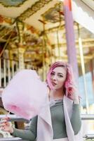 roze haar- meisje kort kapsel poseren in amusement park Aan carrousel achtergrond. foto