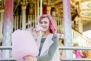 roze haar- meisje kort kapsel poseren in amusement park Aan carrousel achtergrond. foto