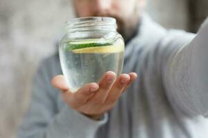 handheld schot van een met een kap Mens drinken water, in langzaam beweging foto