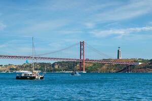 visie van 25 de abril brug over- tagus rivier, Christus de koning monument en een jacht boot. Lissabon, Portugal foto