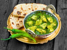 Indisch gezond keuken palak paneer geserveerd met tandoori roti of salade Aan houten achtergrond foto