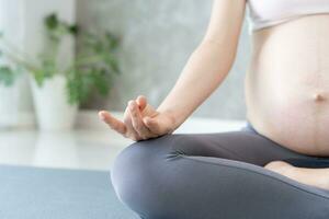 zwanger vrouw aan het doen yoga Aan oefening mat. mediteren voor korte termijn bevalling van mediteren aantrekkelijk zwanger vrouw recreatie en kom tot rust, ademen en kalmte met yoga. zelf zorg foto