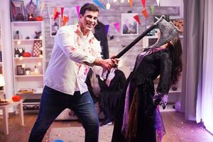 Mens gekleed omhoog Leuk vinden zombie met een bijl proberen naar doden een onheil heks Bij halloween feest. foto
