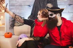mooi vrouw in vampier kostuum nemen een selfie met een piraat Bij halloween feest. foto