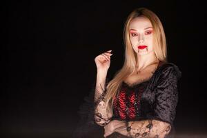 dame van dood met druipend bloed van lippen over- zwart achtergrond. halloween kostuum. foto