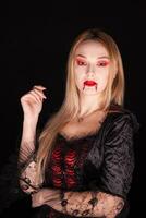 Kaukasisch meisje gekleed omhoog Leuk vinden een vampier voor halloween over- zwart achtergrond. foto
