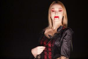 vrouw vervelend een vampier kostuum met een roos over- zwart achtergrond. foto
