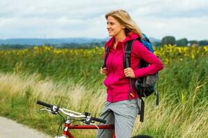 vrouw wandelaar zittend Aan een fiets in de natuur foto