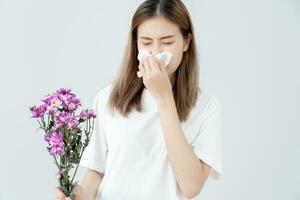 stuifmeel allergieën, Aziatisch jong vrouw niezen in een zakdoek of blazen in een veeg, allergisch naar wild voorjaar bloemen of bloesems gedurende de lente. allergisch reactie, ademhalings systeem problemen foto