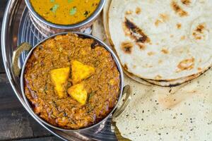 Indisch traditioneel thali voedsel kadai paneer geserveerd met dal makhani Aan wijnoogst houten achtergrond foto