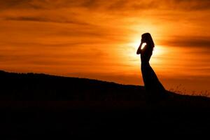 silhouet van een verdrietig vrouw staand Bij de zonsondergang. foto