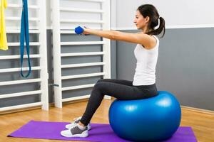 mooi jong vrouw oefenen met gewichten en pilates bal foto