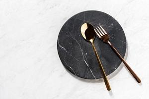 vork en lepel op een zwart marmeren dienblad foto