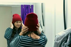 proberen Aan jasje en hoed - middelbare leeftijd vrouw in passend kamer van oppakken punt foto