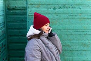 elegant vrouw in vallen kleding hebben een telefoon gesprek binnen wijnoogst strand veranderen stand foto