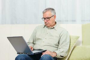 senior Mens gebruik makend van laptop. foto