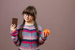 weinig nerd meisje wil eten chocola liever vervolgens fruit foto