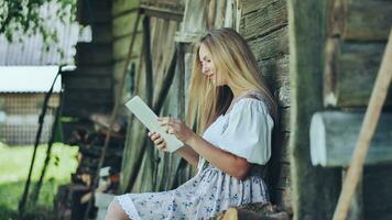 dorp Slavisch meisje flippen een tablet in de platteland. foto