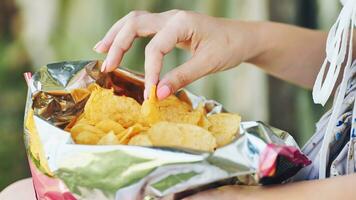 meisje aan het eten chips Aan de straat. detailopname van de handen. foto