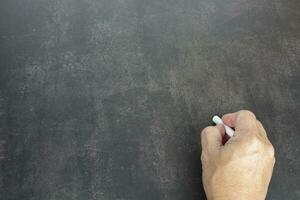 mannenhand schrijft in wit krijtpotlood op een schoolbordachtergrond. ruimte kopiëren. foto