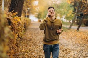 gelukkige kerel die lacht en praat aan de telefoon in het herfstpark foto