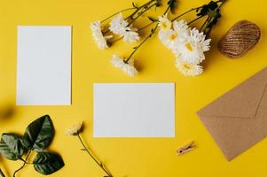 een blanco kaart met envelop en bloem wordt op een gele achtergrond geplaatst foto