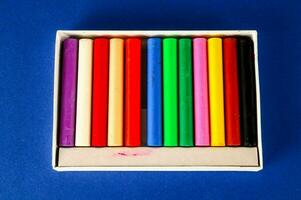 een doos van gekleurde kleurpotloden Aan een blauw achtergrond foto