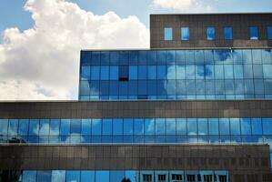 glas gebouw met transparant facade van de gebouw en blauw lucht. structureel glas muur reflecterend blauw lucht. abstract modern architectuur fragment. hedendaags bouwkundig achtergrond. foto