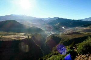 de zon schijnt helder over- een vallei in de bergen foto