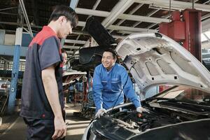 Aziatisch mannetje professioneel automotive ingenieur leidinggevende beschrijft auto motor onderhoud en reparatie werk met monteur arbeider personeel team in fix onderhoud garage, specialist beroepen in auto industrie. foto