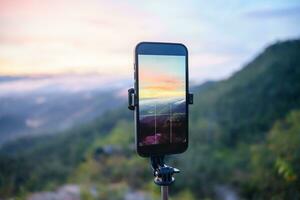 smartphone nemen foto van berg stroom met statief natuur visie Aan scherm Bij zonsondergang