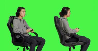 vrolijk persoon geniet online spelen, zittend Aan gaming stoel over- groene scherm geïsoleerd achtergrond in studio. jong Aziatisch vent hebben pret met wedstrijd, Mens spelen video spellen. foto