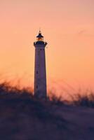 vuurtoren in warm ochtend- gloed bovenstaand de duinen foto