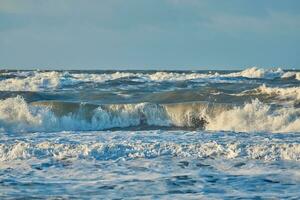 reusachtig breken golven Bij noorden zee kust foto