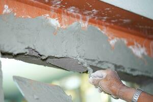 detailopname handen van bouwer Holding Mortier pan en bepleistering muren met cement in bouw plaats. foto