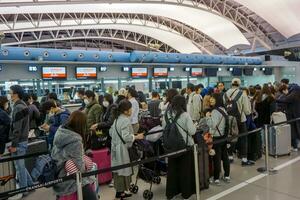 Osaka stad, Japan, 2019 - beeld van veel toeristen aan het wachten voor controleren in voorkant van vliegmaatschappij teller in de luchthaven naar terugkeer zijn land of gaan naar reizen een ander land. foto