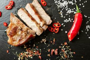 varkensvlees gekookt in een pan en in stukjes gesneden met kruiden op een donkere stenen achtergrond foto