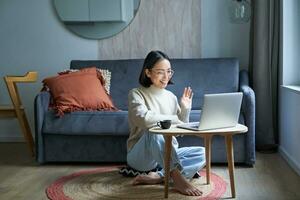 portret van jong werken vrouw, Koreaans meisje aan het studeren Aan afgelegen online, pratend naar laptop, video chatten, heeft gesprek via computer toepassing foto