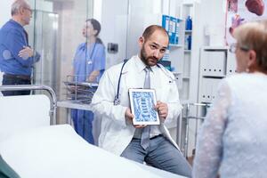 dokter tonen radiologie scannen naar senior geduldig na medisch controleren in ziekenhuis examen kamer. medisch Diensten geneeskunde gezondheidszorg welzijn steun, arts werken foto