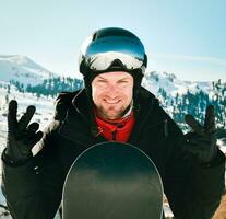 Kaukasisch snowboarder Mens vervelend ski stofbril en kleurrijk ski apparatuur, tonen duimen omhoog Aan helling foto