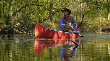 cowboy in een kano drijft Aan de rivier- in de Woud. historisch wederopbouw van leven in de wild west van Amerika foto