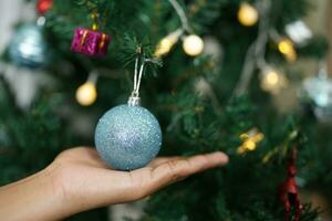 vrolijk Kerstmis 2024 concept Aziatisch Dames versieren de Kerstmis boom met kleurrijk Kerstmis ballen. foto