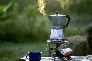 mokka pot en rook, koffie koesteren Aan vuur, in de Woud Bij zonsopkomst in de ochtend. zacht focus. Ondiep focus effect. foto