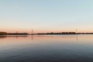 kleurrijk water oppervlakte en lucht gedurende zonsondergang in zomer in almere, Nederland foto